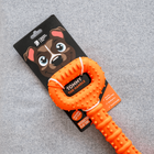 Close-up of The Tommy Tug Handle dog toy in orange with product packaging on display.